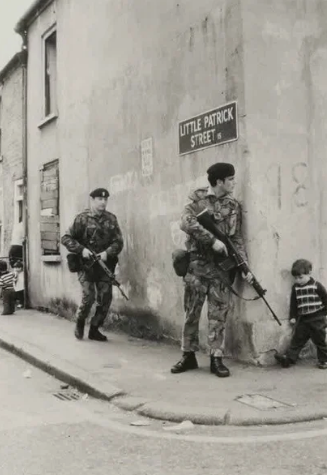 Маленький мальчик, идущий к своим друзьям, сталкивается с британскими солдатами за углом в Белфасте, Северная Ирландия. (1973)